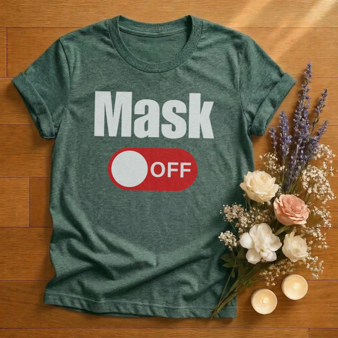 Green heather t-shirt with 'Mask Off' graphic on a wooden surface with flowers and candles.